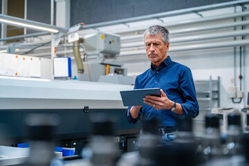 Senior worker using tablet PC at industry