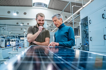 Smiling co workers checking solar panel at factory