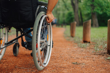 Patient using wheelchair moving on a path in park surrounded by green grass