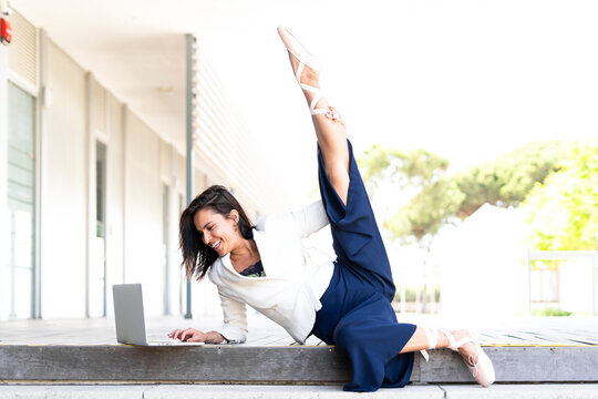 Female ballet dancer using laptop sitting on steps