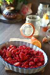 Close-up view of a bowl filled with fresh strawberries and red currants, prepared for baking. A delicious homemade fruit crumble