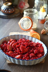 Close-up view of a bowl filled with fresh strawberries and red currants, prepared for baking. A delicious homemade fruit crumble
