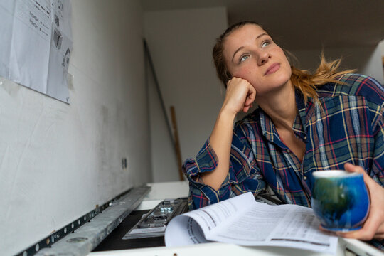 Young woman with assembly instructions in kitchen looking away