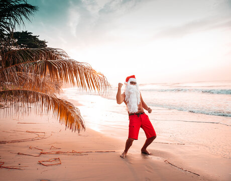 Thailand, man dressed up as Santa Claus posing on the beach at sunset