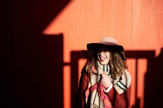 Laughing woman wearing a floppy hat in light and shadow