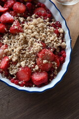 Close-up view of a bowl filled with fresh strawberries and red currants, prepared for baking. A delicious homemade fruit crumble