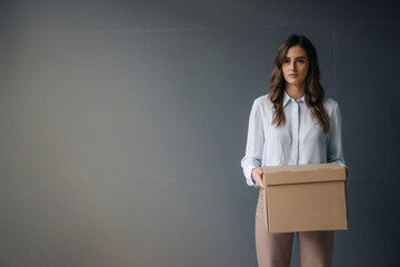 Serious young businesswoman holding cardboard box