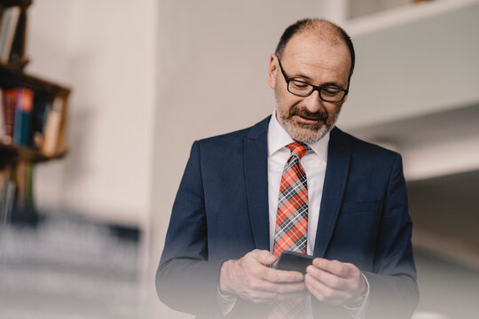 Mature businessman using cell phone in a cafe - Powered by Adobe