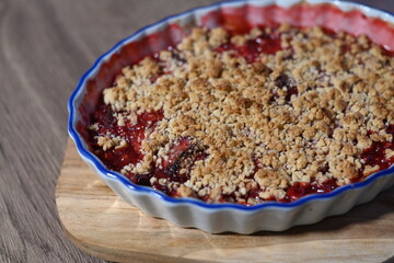 The dessert is freshly baked, with juicy, bubbling fruit filling visible beneath the crunchy crumble layer. Fruit crumble, homemade baking cake