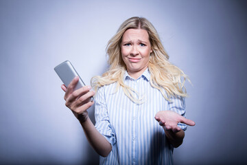 Portrait of asking blond woman with smartphone