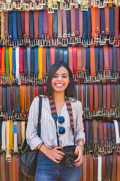 Italy, Florence, portrait of happy young tourist with backpack and camera on street market