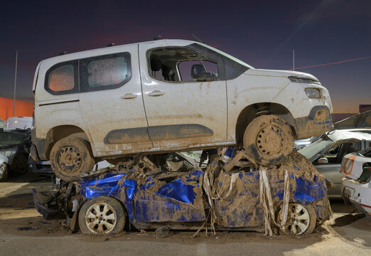 Damaged cars stacked on each other in junkyard at night