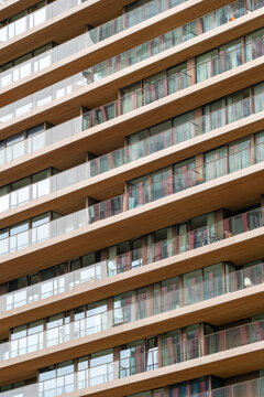 The image features a modern apartment building showcasing multiple sleek balconies and large glass windows, emphasizing contemporary architectural design and urban living.
