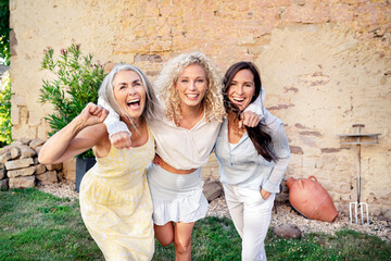 Portrait of three excited women of different age embracing and cheering