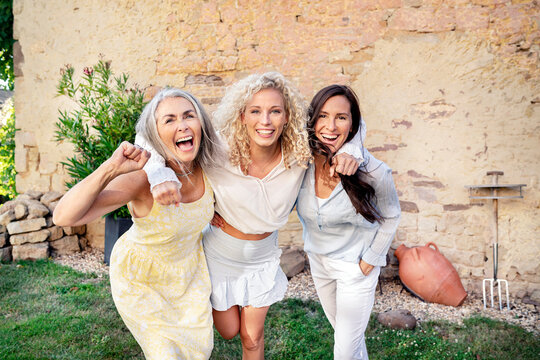 Portrait of three excited women of different age embracing and cheering
