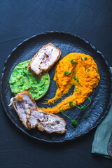 Chicken Cordon Bleu with carrot puree and spinach mashed potatoes on a black board top view. A traditional French dish in an original presentation. Healthy eating and diet concept.