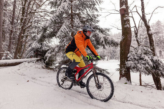 Man riding mountainbike on path in winter forest