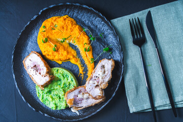 Chicken Cordon Bleu with carrot puree and spinach mashed potatoes on a black board top view. A traditional French dish in an original presentation. Healthy eating and diet concept.