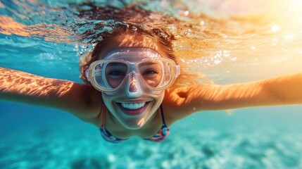 Fototapeta premium Woman enjoys snorkeling underwater, smiling with happiness in the bright ocean water