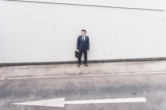 Businessman standing at road with arrow sign