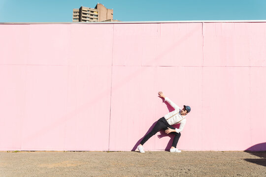 Young man in front of pink construction barrier, touching wall