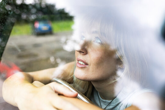 Smiling young beautiful woman looking through car window