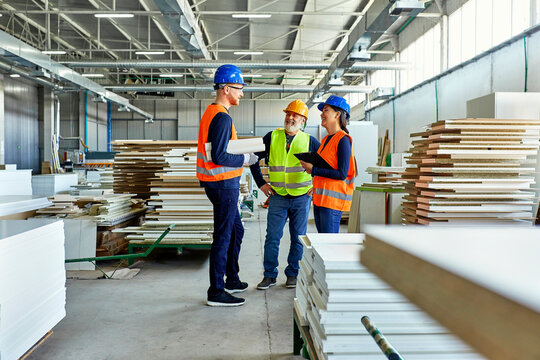 Colleagues in protective workwear talking in factory