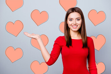 Selling time, discounts for 14 February, nice, cute woman showing copy space on her palm, looking at camera, standing over gray background