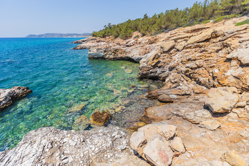 Crystal Clear Waters and Rocky Shoreline in Greece, Sunny Summer Day