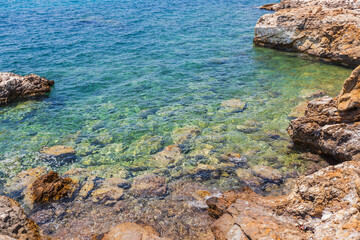 Crystal Clear Waters and Rocky Shoreline in Greece, Sunny Summer Day