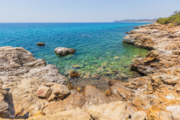 Crystal Clear Waters and Rocky Shoreline in Greece, Sunny Summer Day
