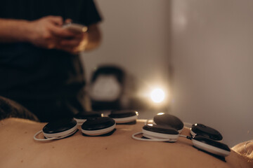 Lower Back Physical Therapy with TENS Electrode Pads, Transcutaneous Electrical Nerve Stimulation. Therapist Positioning Electrodes onto Patient's Lower Back