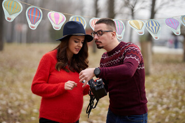 Expecting couple reviewing maternity photos outdoors