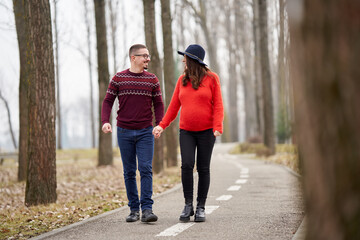 Fototapeta premium Expecting couple walking hand in hand outdoors