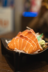 Elegantly arranged salmon sashimi slices and a dab of wasabi, presented on a plate