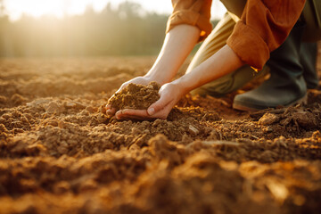 Young female farmer's hands holding soil, earth, black soil earth fertilizers. Gardening and ecology concept.