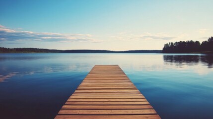 Fototapeta premium Serene lake view with wooden dock extending to calm water under a clear sky.