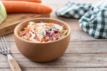 Coleslaw salad in wooden bowl on wooden table. Copy space