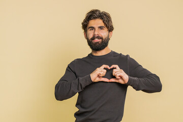 I love you. Smiling happy Lebanese young man makes heart gesture demonstrates love sign expresses...