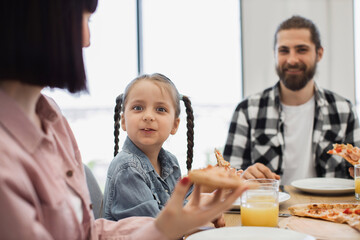 Caucasian family with young daughter enjoying breakfast together at home. Family bonding, happiness, sharing meal, and casual morning setting.