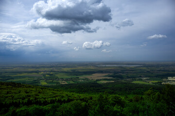 Cloudy day view from hilltop over green fields.