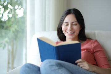 Happy asian woman reading a paper book at home