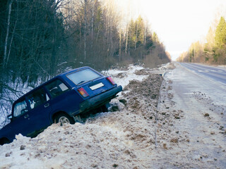 An abandoned car on the side of the road after a traffic accident. Symbolizes dangerous driving conditions in winter and icy conditions