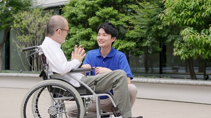 車椅子の高齢者と話をする介護士