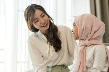 Fototapeta premium Muslim mother adjusts her daughter hijab with love and care between parent and child, showcasing cultural tradition, affection and connection, islamic family bond, focus on motherly love