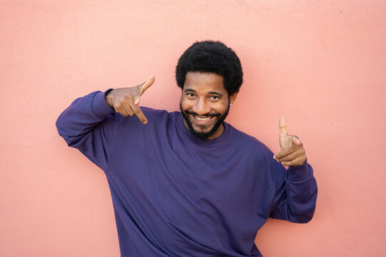 Cheerful man in purple t-shirt against pink background