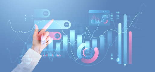 Hand interacting with futuristic digital financial graphs and charts on blue background.