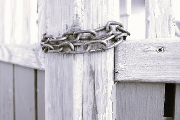 A Rusty Chain Lock Securing a Weathered and Timeworn Wooden Gate Set Against Natures Beauty