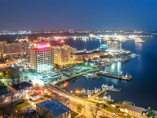 Fototapeta premium Coastal Cityscape Illuminates at Night with Vibrant Lights and Boats Docked Serenely Under the Starry Sky
