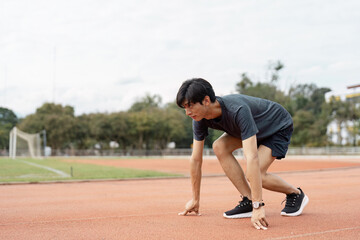 Determined young man preparing to sprint on a track, focused on his fitness and athletic training